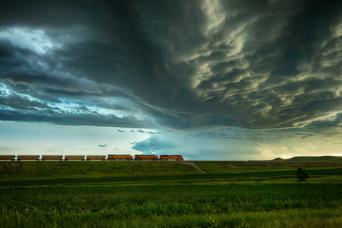 Empty coal unit train rolls through plains under an ominous sky
